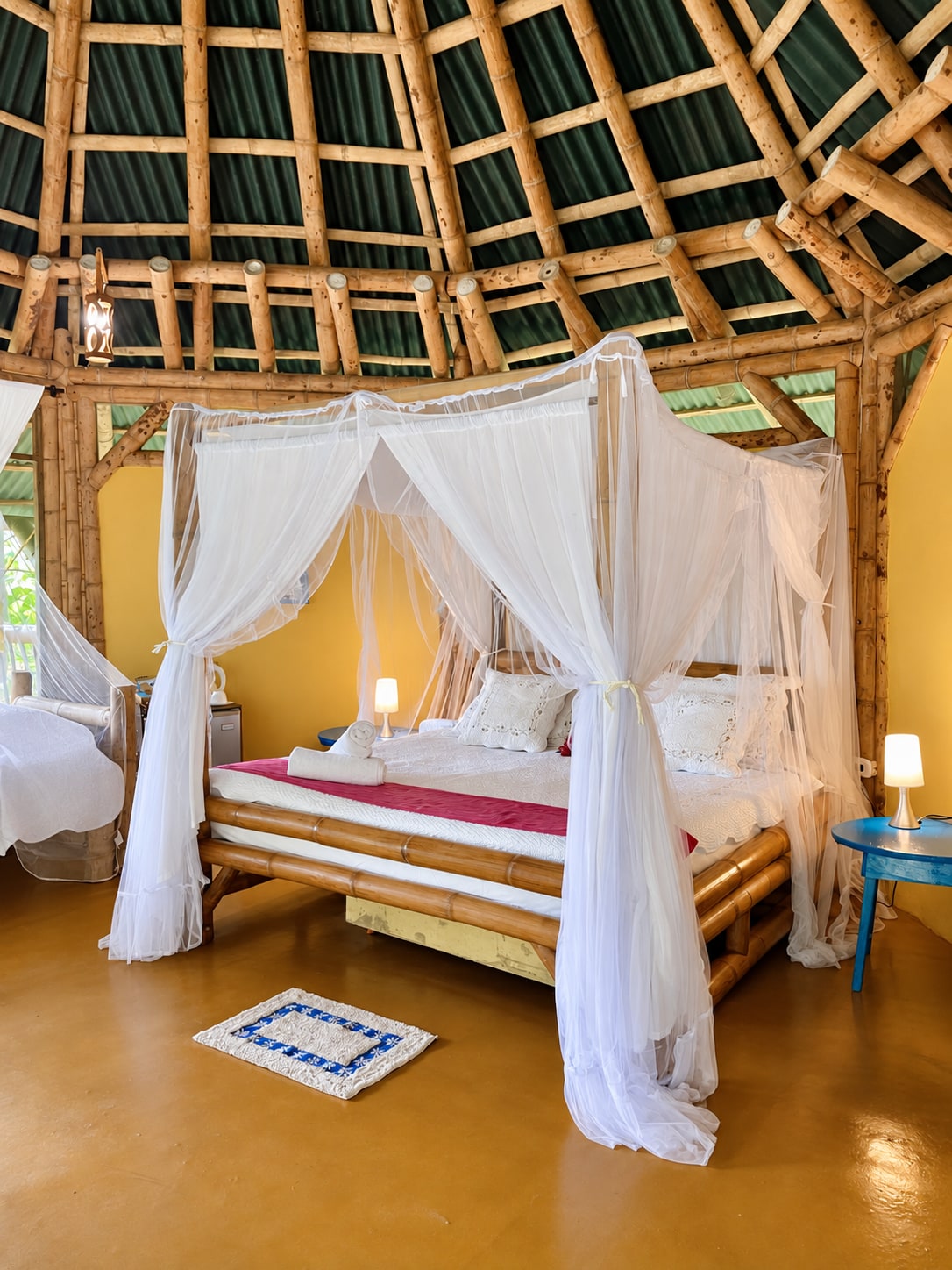 Habitación con cama bajo toldillo y cúpula de guadua